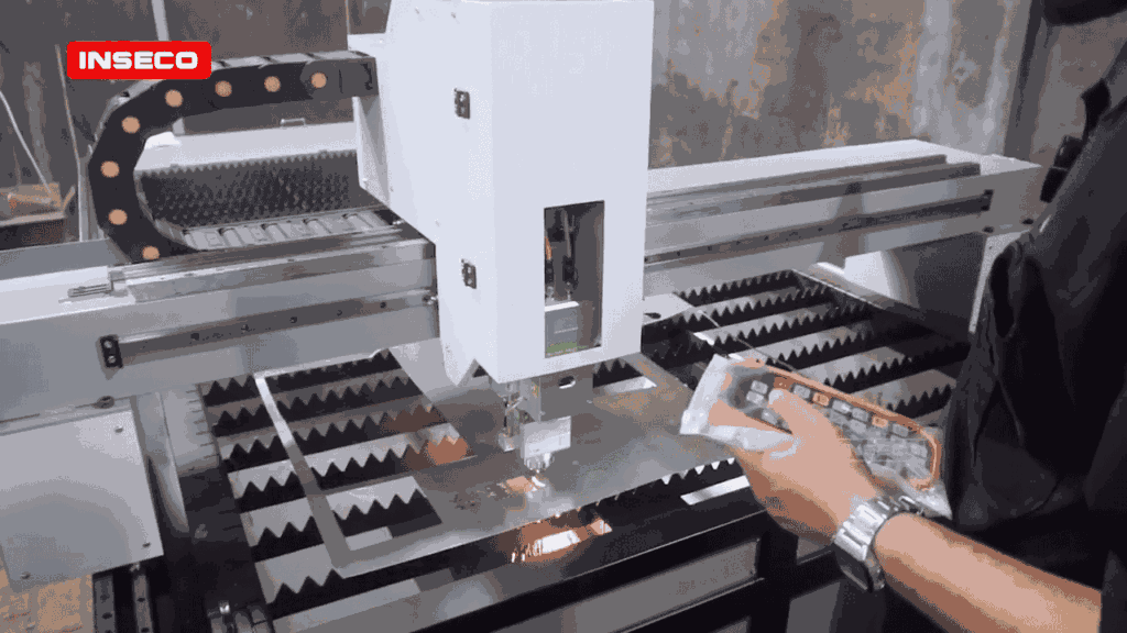 Peluang Pasar dan Segmentasi Bisnis Laser Cutting Plat di Era Industri 4.0 5 Operator mengontrol mesin fiber laser INSECO menggunakan remote wireless pendant saat proses pemotongan plat logam. Terlihat percikan api hasil pemotongan yang presisi dengan sistem servo motor 3-axis. Mesin laser cutting berkualitas tinggi dengan harga terjangkau untuk memulai usaha.