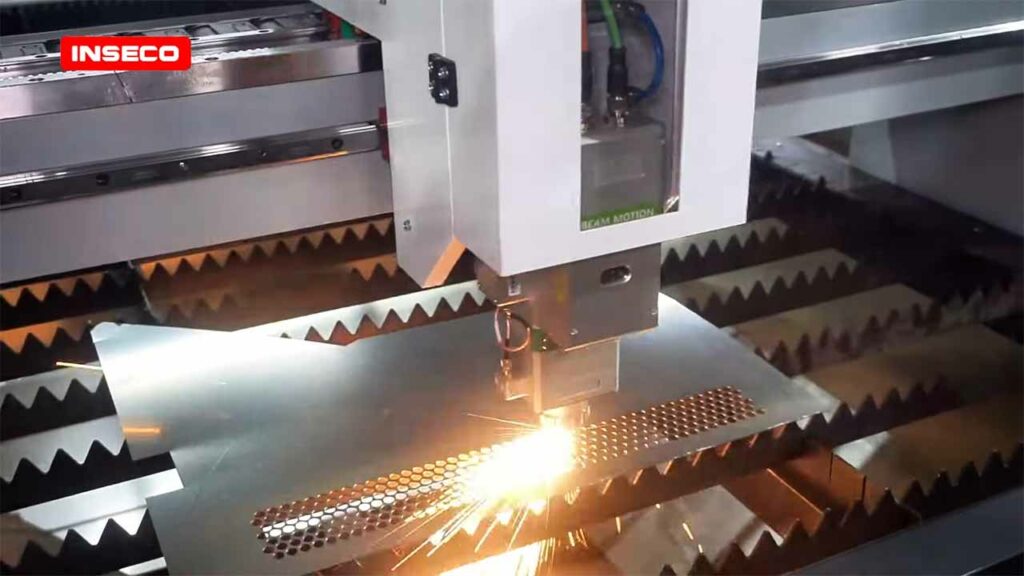 Mesin laser cutting Inseco sedang memotong plat logam, percikan api terlihat di titik potong.