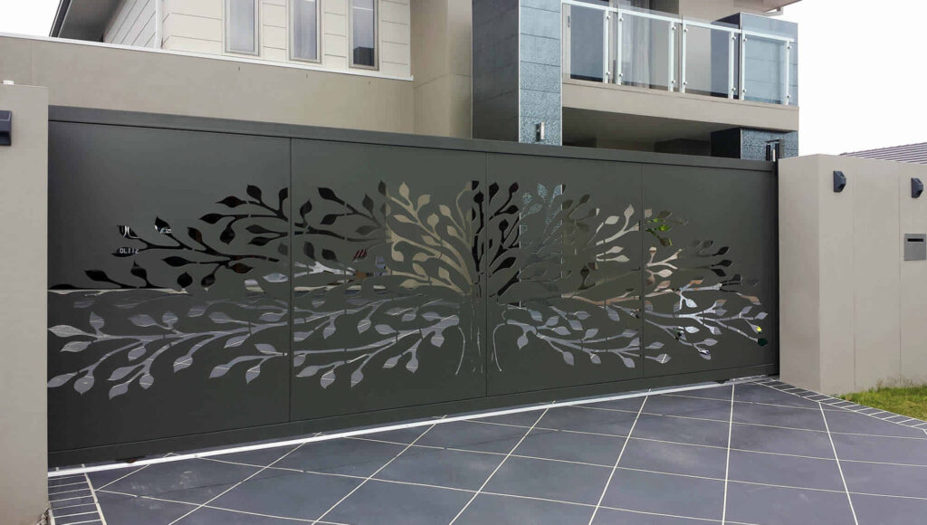Pagar cutting laser minimalis motif pohon di gerbang geser, berwarna abu-abu gelap, cocok untuk rumah modern dengan desain elegan dan presisi tinggi